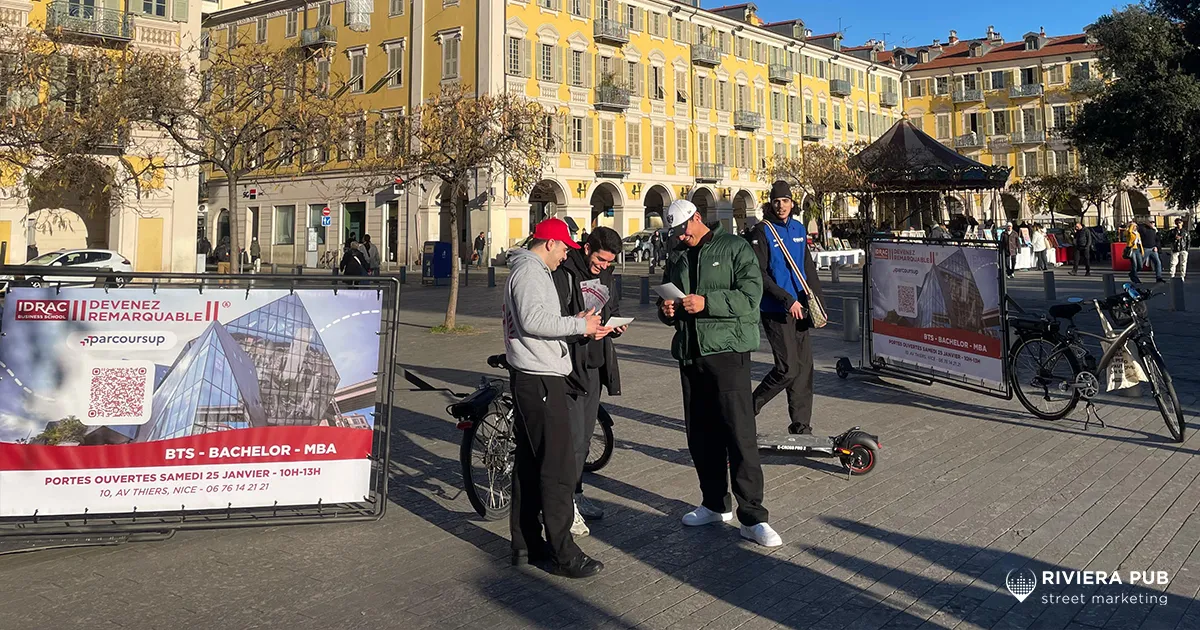 Hôtes distribuant des flyers IDRAC avec goodies et vélos publicitaires dans le centre-ville de Nice